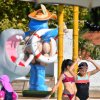 Bambini giocano con spruzzi d'acqua accanto a una statua di ippopotamo in un parco acquatico.