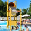 Bambini si divertono sotto un secchio gigante che versa acqua in piscina.