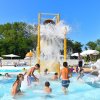 Una grande piscina circondata da lettini e alberi verdi.