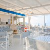Bar sulla spiaggia con tavoli bianchi e sedie grigie.