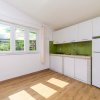 Cucina luminosa con mobili bianchi e parete verde.