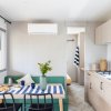 Interno moderno con tavolo apparecchiato, divano verde e cucina attrezzata.