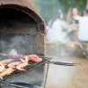 Cibo, tra cui gamberi e polpo, griglia su barbecue con persone sedute sullo sfondo.