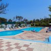 Due piscine all'aperto con lettini e ombrelloni, circondate da vegetazione e un cielo blu.