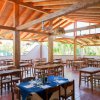 Ristorante con tavoli apparecchiati, soffitto in legno e ampie finestre.
