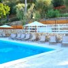 Piscina azzurra con lettini e ombrelloni bianchi.