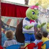 Una mascotte di tartaruga verde interagisce con i bambini seduti.