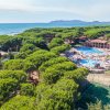 Vista aerea di un resort con piscine, tra pini e vicino al mare.