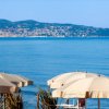 Ombrelloni beige su una spiaggia con vista sul mare e un promontorio in lontananza.