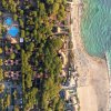 Vista aerea di un villaggio turistico con piscine, pineta e spiaggia.