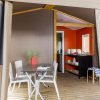 Interno di una tenda con tavolo e sedie, cucina in fondo.