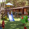 Parco giochi con scivolo blu e giochi a molla su erba sintetica.