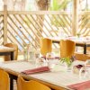 Tavola apparecchiata con bicchieri e fiori in un ristorante all'aperto.