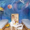 Stanza per bambini con pareti a tema spazio e due letti singoli.
