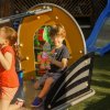 Due bambini giocano su una struttura in un parco giochi; uno tiene un giocattolo.