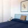 Una camera da letto con copriletto blu, quadro sulla parete e comodino con lampada.