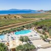 Piscine in un'area aperta, vista sul mare e una collinetta in lontananza.