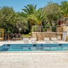 Una piscina all'aperto circondata da lettini, palme e vegetazione.
