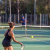 Donna in abbigliamento sportivo gioca a tennis su un campo all'aperto.