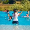 Lezione di nuoto in piscina con istruttrice e partecipanti.
