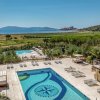 Piscina con decorazioni sul fondo, circondata da lettini, con vista su colline e mare.
