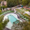 Piscina con lettini, alberi circostanti e una terrazza.