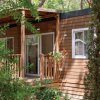 Bungalow in legno con vegetazione circostante.