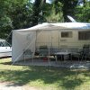 Camper con veranda e sedie vicino a un'auto.