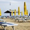 Una spiaggia con lettini e ombrelloni gialli e blu chiusi, vicino al mare.
