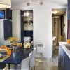 Interno di un camper con tavolo apparecchiato, cucina e TV accesa.