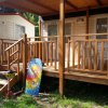 Bungalow con veranda in legno, monopattino e tavola da bodyboard colorata.