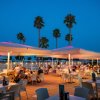 Ristorante all'aperto illuminato di sera con palme.