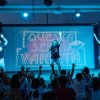 Spettacolo sul palco con bambini davanti.