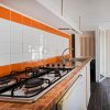 Cucina moderna con piastrelle arancioni e piano cottura a gas.
