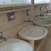 Lavabi bianchi allineati in un bagno con piastrelle beige.