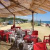 Area di ristoro all'aperto con sedie rosse e bianche, vista mare.