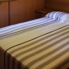 Una camera da letto con letto matrimoniale e copriletto a righe. Pareti in legno chiaro.