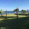 Un camper vicino a un prato verde con vista sul mare e palme.