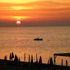 Un tramonto sul mare con ombrelloni in silhouette sulla spiaggia.