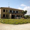 Una casa a due piani con persiane verdi, un ampio prato e un recinto di legno.