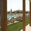Piscina con lettini e ombrelloni, vista attraverso colonne in legno.