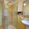Bagno con box doccia, lavabo bianco e pareti con piastrelle gialle.