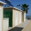Area docce sulla spiaggia con cabine e ombrelloni sullo sfondo.