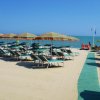 Spiaggia con lettini e ombrelloni colorati, cielo azzurro e mare calmo.