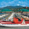 Spiaggia con sdraio, ombrelloni verdi e barca da salvataggio.