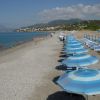 Una spiaggia con ombrelloni azzurri allineati e persone che nuotano nel mare.