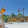 Un parco acquatico con giochi a tema pirata e bambini che giocano sotto gli spruzzi d'acqua.