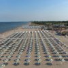 Una spiaggia con file ordinate di ombrelloni gialli e blu.