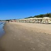 Lunga spiaggia con ombrelloni bianchi e cielo limpido.