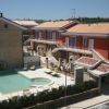 Edificio residenziale moderno con piscina e lettini in un cortile soleggiato.